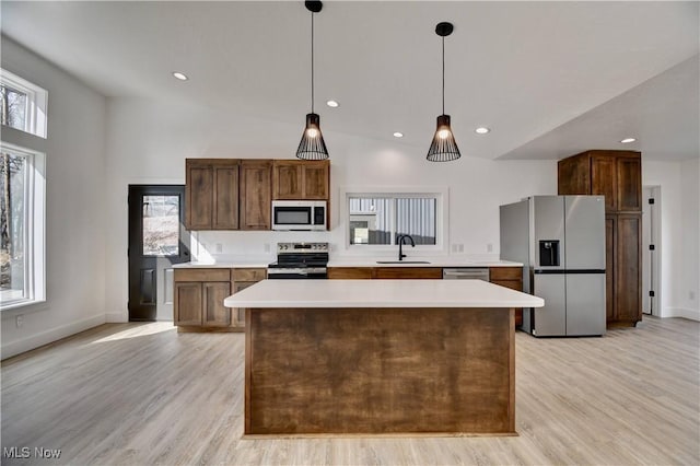 kitchen with light wood-type flooring, appliances with stainless steel finishes, light countertops, and a sink