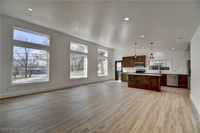 kitchen with a center island, stainless steel appliances, light countertops, open floor plan, and a sink