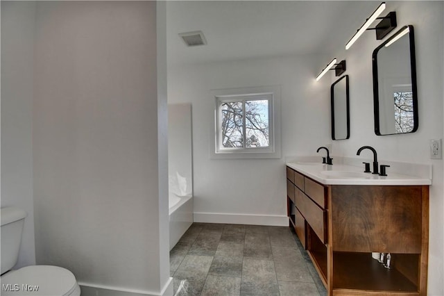 bathroom featuring baseboards, a sink, toilet, and double vanity