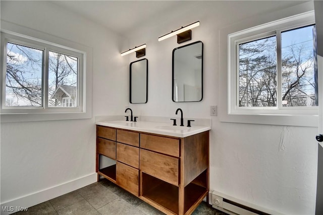 full bathroom featuring double vanity, a baseboard radiator, a sink, and a healthy amount of sunlight