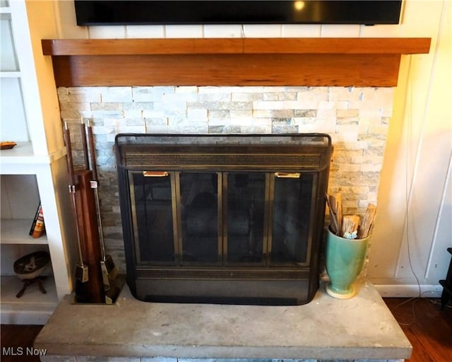 details featuring wood finished floors and a glass covered fireplace