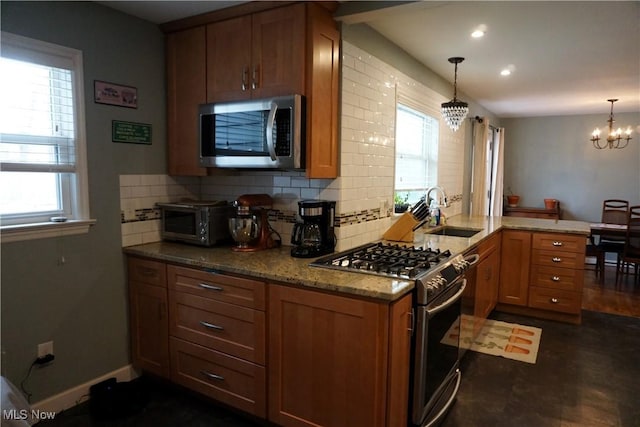 kitchen featuring a peninsula, appliances with stainless steel finishes, backsplash, and a sink