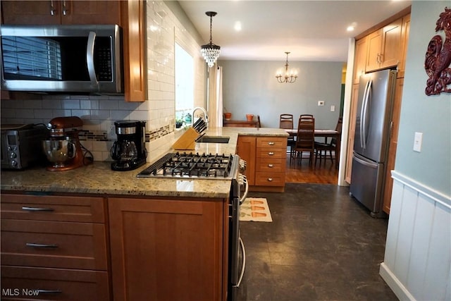 kitchen with tasteful backsplash, light stone countertops, stainless steel appliances, a chandelier, and a sink