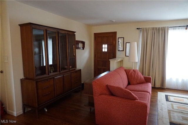 living area with plenty of natural light and dark wood-type flooring