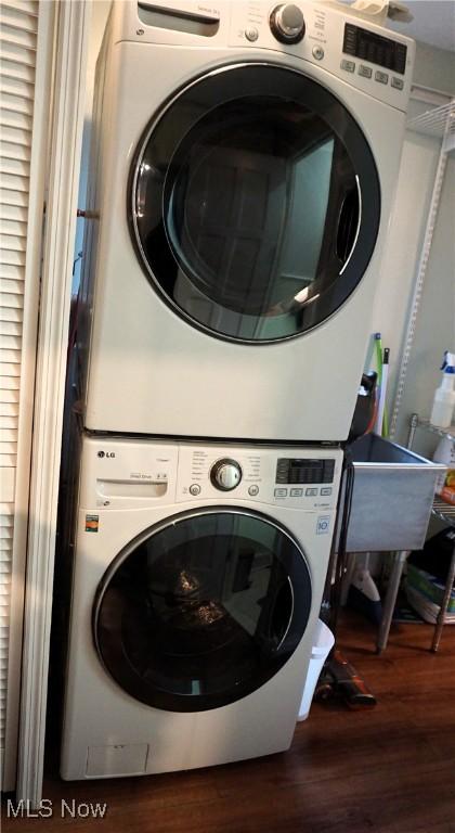 laundry room with laundry area, stacked washing maching and dryer, and wood finished floors