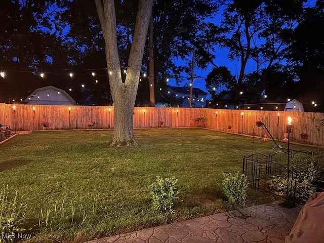 yard at night featuring a fenced backyard