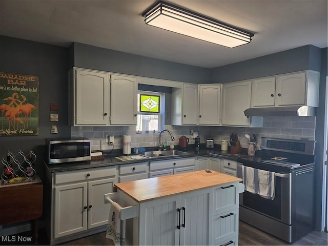 kitchen featuring white cabinets, appliances with stainless steel finishes, under cabinet range hood, wooden counters, and a sink