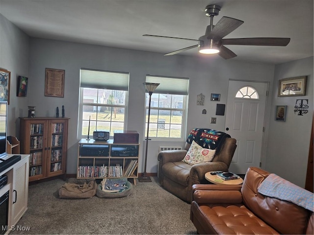 carpeted living area with ceiling fan and baseboards