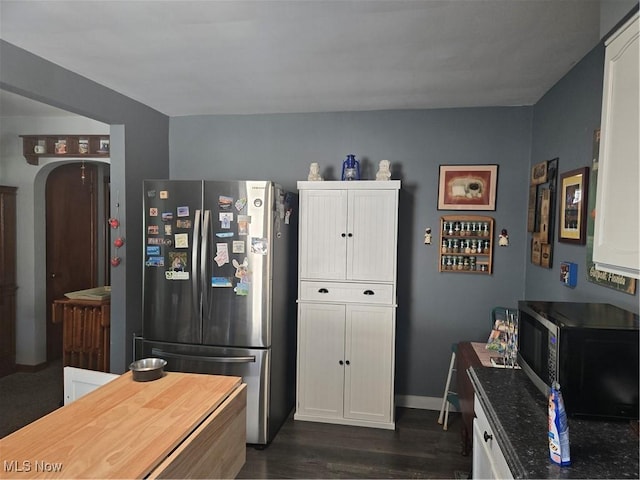 kitchen featuring arched walkways, dark wood-style flooring, appliances with stainless steel finishes, white cabinetry, and baseboards