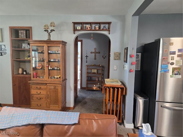 dining room with arched walkways, dark carpet, and baseboards