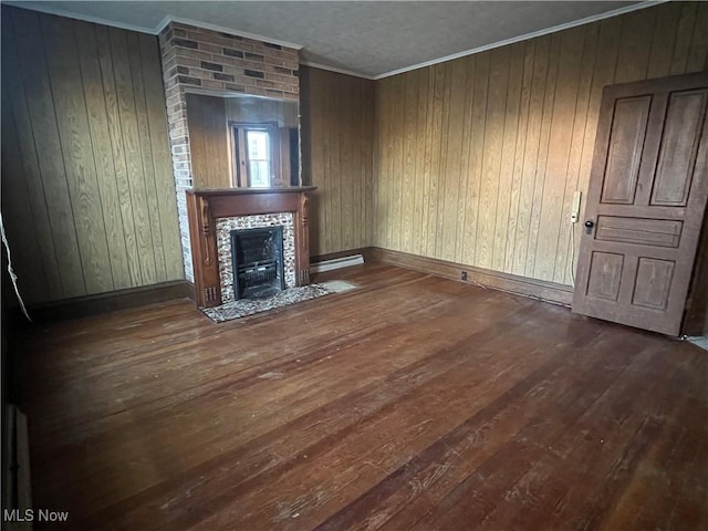 unfurnished living room featuring a baseboard radiator, wood walls, a fireplace, ornamental molding, and hardwood / wood-style floors