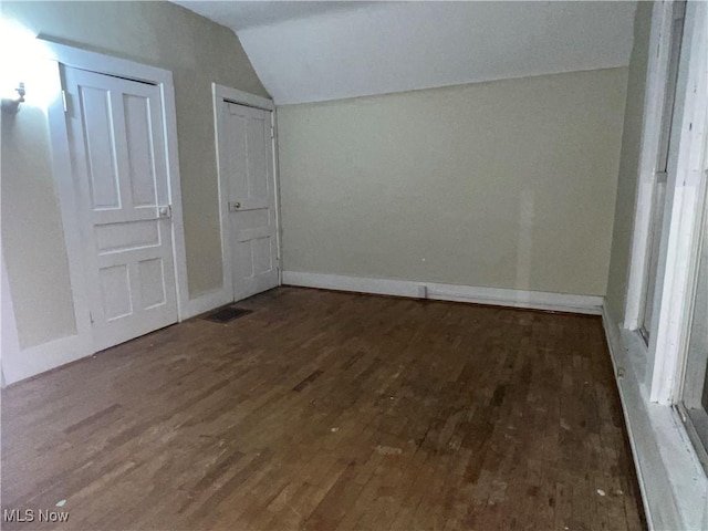 unfurnished bedroom with vaulted ceiling, baseboards, and wood finished floors