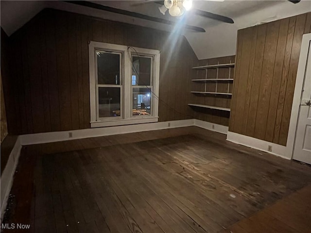 bonus room with wood walls, a ceiling fan, vaulted ceiling, and hardwood / wood-style floors