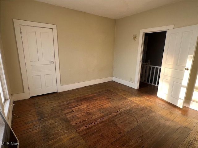 unfurnished bedroom with dark wood-style flooring and baseboards