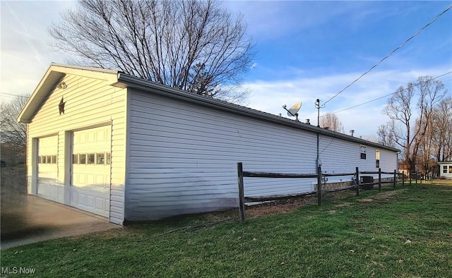 view of side of home featuring a garage, an outbuilding, fence, and a lawn