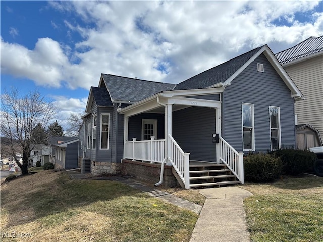 view of front of house featuring a porch, a shingled roof, and a front lawn