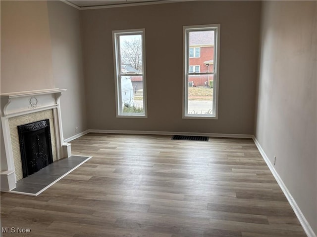 unfurnished living room featuring baseboards, a wealth of natural light, and a tile fireplace