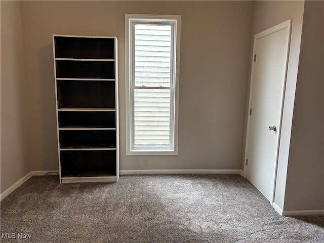 unfurnished bedroom with baseboards, multiple windows, and carpet flooring