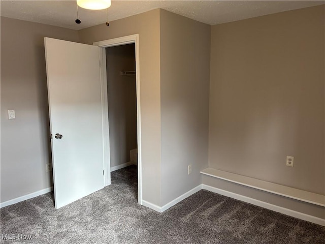 unfurnished bedroom featuring dark colored carpet and baseboards