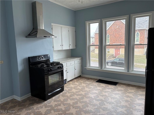 kitchen featuring visible vents, white cabinetry, light countertops, wall chimney exhaust hood, and black appliances