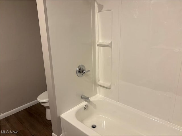 full bathroom featuring bathing tub / shower combination, wood finished floors, toilet, and baseboards