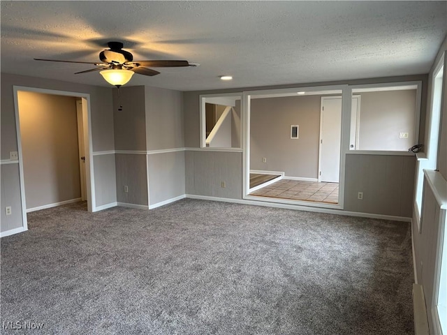 carpeted spare room with a textured ceiling, a ceiling fan, and baseboards