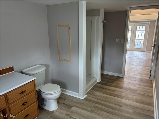 full bathroom with toilet, baseboards, a shower, and wood finished floors