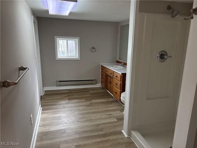 full bathroom with a baseboard radiator, walk in shower, wood finished floors, and vanity