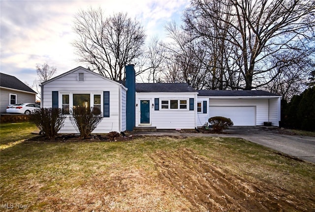 single story home featuring driveway, entry steps, a chimney, an attached garage, and a front yard