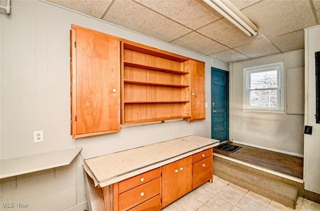 interior space featuring light countertops, light tile patterned flooring, open shelves, and a paneled ceiling