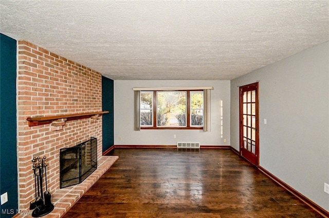 unfurnished living room with baseboards, a fireplace, visible vents, and wood finished floors