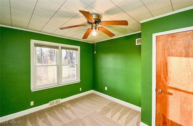 spare room with carpet floors, baseboards, visible vents, and crown molding