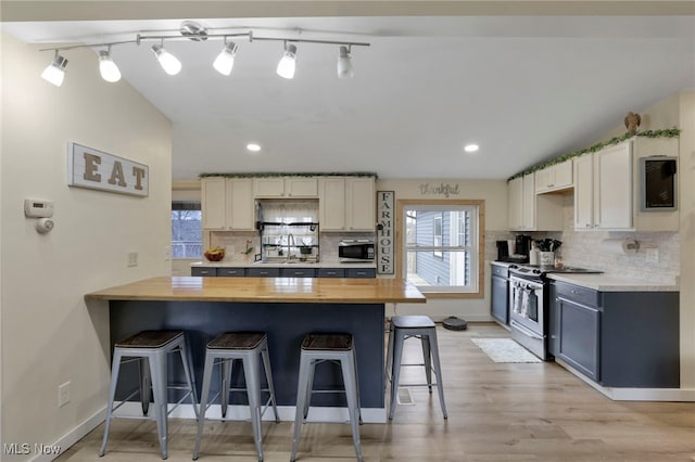 kitchen with stainless steel appliances, wooden counters, a peninsula, and a kitchen breakfast bar