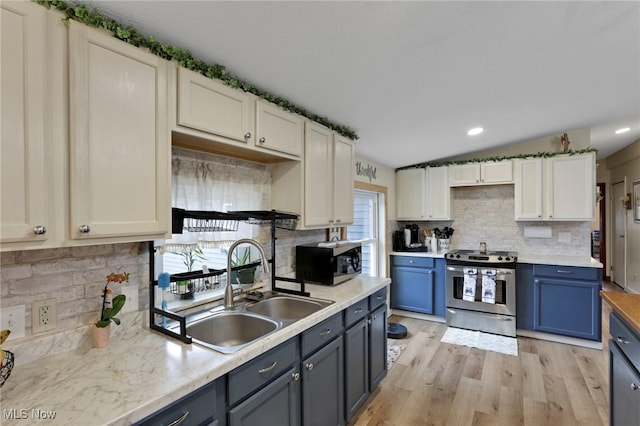 kitchen with appliances with stainless steel finishes, blue cabinets, light countertops, light wood-style floors, and a sink