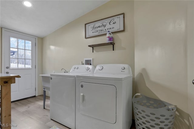 clothes washing area with laundry area, light wood finished floors, and washing machine and dryer