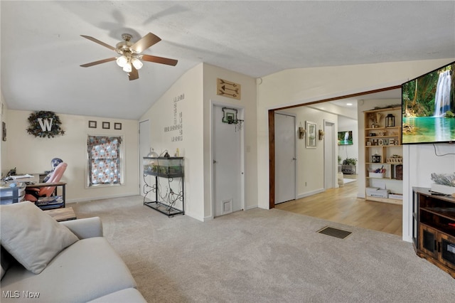 living area with a ceiling fan, carpet flooring, vaulted ceiling, and visible vents