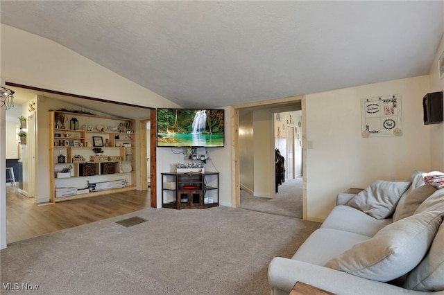 carpeted living area featuring visible vents, vaulted ceiling, a textured ceiling, and baseboards