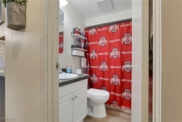 full bathroom with wood finished floors, a shower with shower curtain, vanity, and toilet