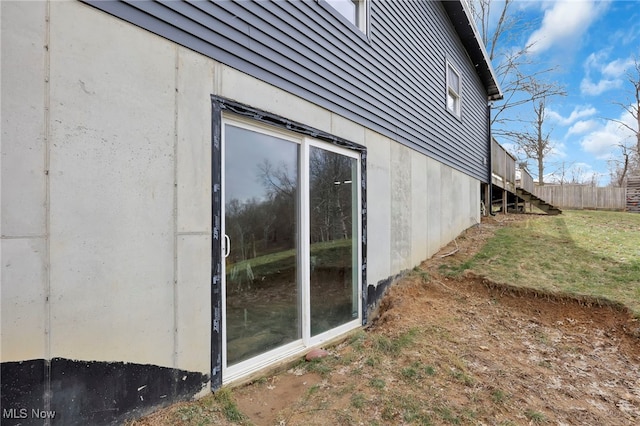 view of property exterior featuring stairway, fence, and a lawn