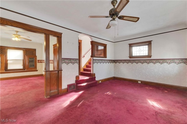 carpeted empty room with a wainscoted wall, visible vents, stairway, and wallpapered walls