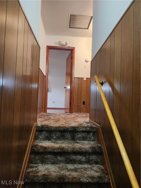 staircase featuring wood walls and visible vents