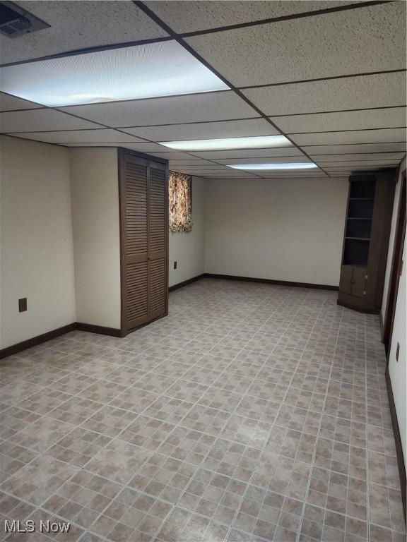 finished basement with visible vents, baseboards, and a drop ceiling