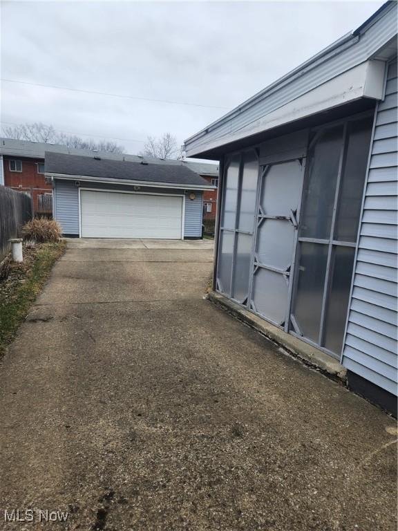 view of side of home featuring a garage, an outbuilding, and fence