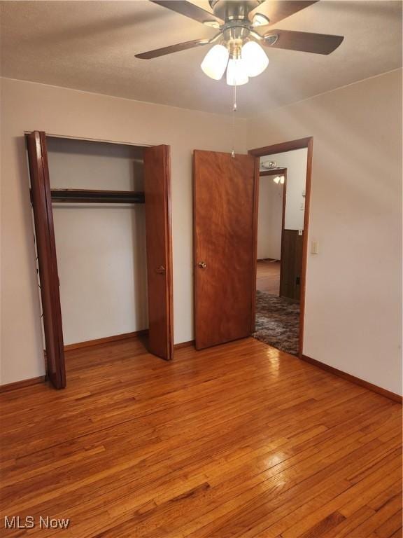 unfurnished bedroom with a closet, baseboards, ceiling fan, and hardwood / wood-style floors