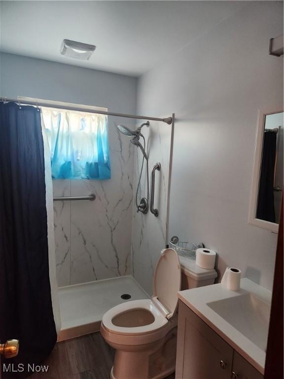 bathroom with toilet, wood finished floors, vanity, visible vents, and a marble finish shower