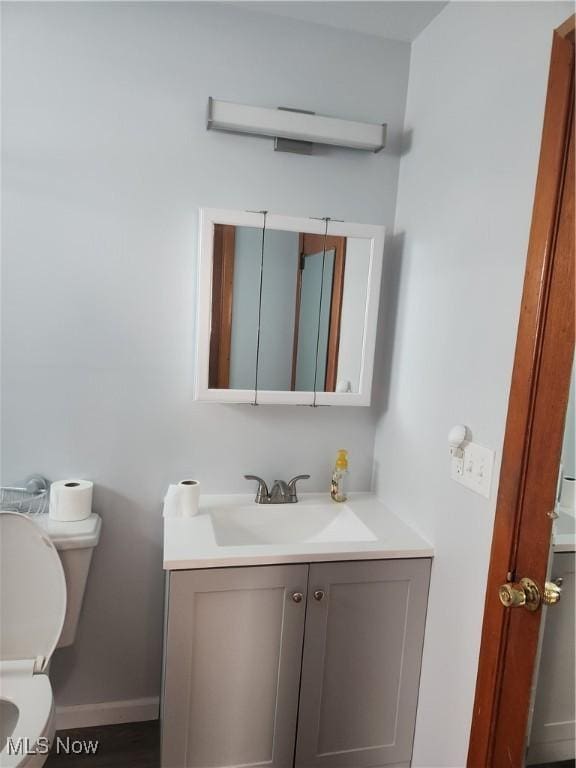 bathroom featuring toilet, baseboards, and vanity