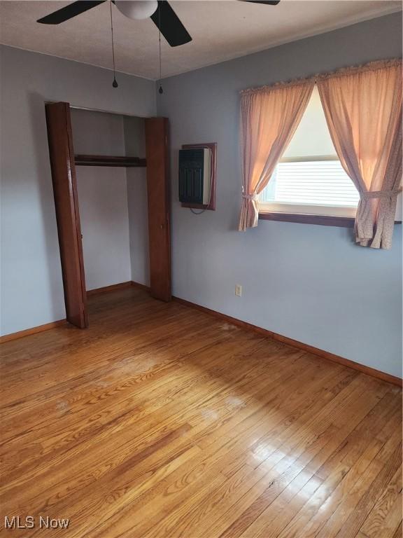 unfurnished bedroom featuring light wood finished floors, a ceiling fan, and baseboards