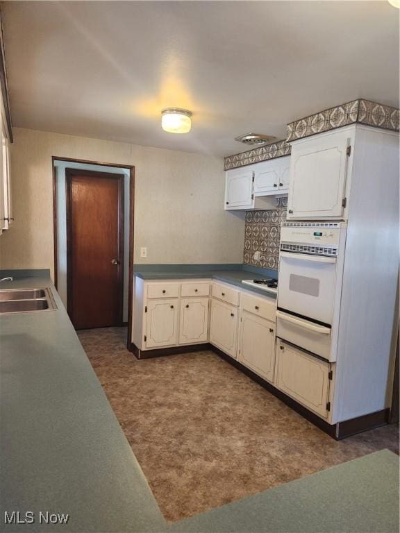 kitchen featuring white appliances, dark floors, a sink, backsplash, and a warming drawer