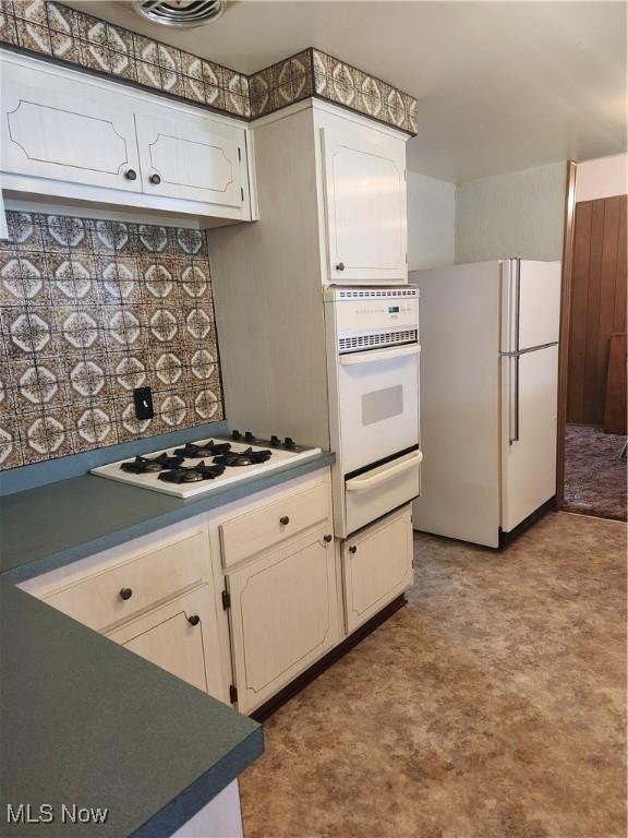 kitchen featuring white appliances, white cabinets, a warming drawer, and tile patterned floors