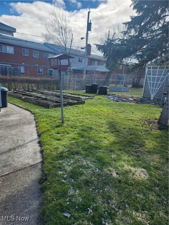 view of property's community featuring a garden, fence, and a yard